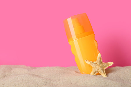 Suntan product and starfish on sand against pink background. Space for textの写真素材