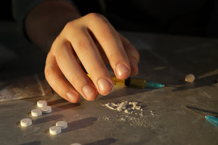 Addicted man with drugs at gray textured table, closeup