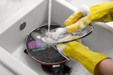 Woman washing dirty dishes in kitchen sink, closeupの写真素材
