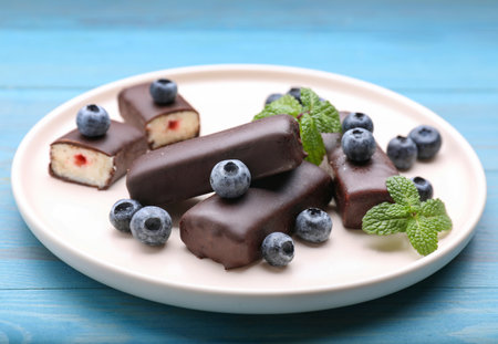 Delicious glazed curd snacks with fresh blueberries and mint on light blue wooden tableの写真素材