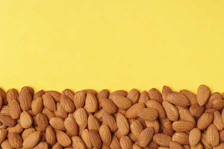 Delicious raw almonds on yellow background, flat lay. Space for textの写真素材