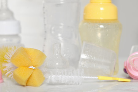 Clean baby bottles after sterilization near brushes on white table, closeupの写真素材