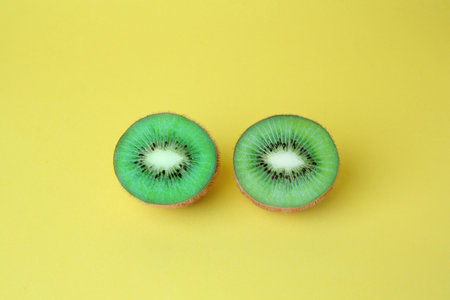Cut fresh ripe kiwis on yellow background, above viewの写真素材