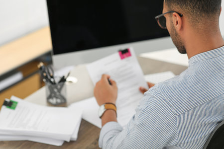 Man working with documents at wooden table in office, closeupの写真素材