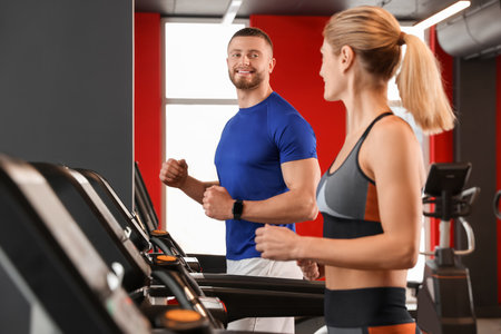 Beautiful couple training on treadmills in gymの写真素材