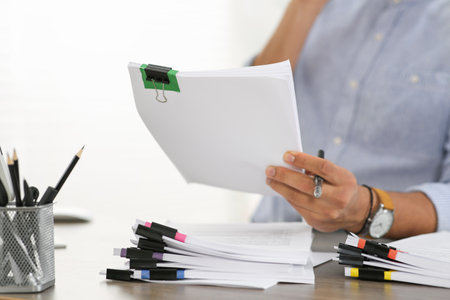 Man working with documents at wooden table in office, closeupの写真素材