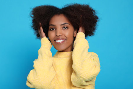 Portrait of smiling African American woman on light blue background