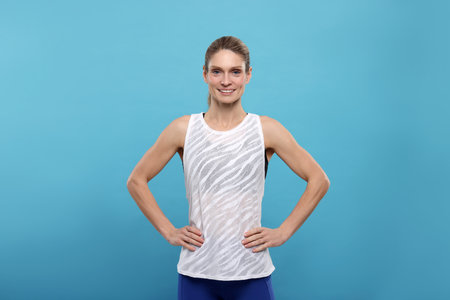 Portrait of happy sportswoman on light blue backgroundの写真素材
