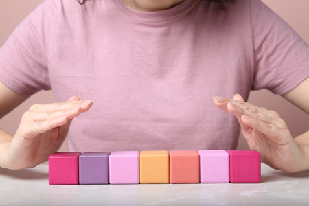 Woman demonstrating empty colorful cubes at gray marble table, closeup. space for designの写真素材