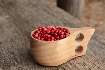 Cup with tasty ripe lingonberries on wooden table, space for textの写真素材