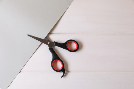 Scissors and paper on white wooden background, top view. Space for textの写真素材