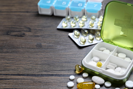 Pill box with medicines on wooden table. Space for text