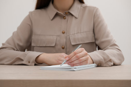 Woman writing in notebook at wooden table, closeupの写真素材