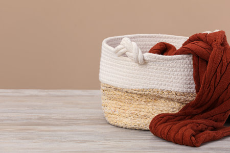 Wicker laundry basket with clothes near beige wall. Space for textの写真素材