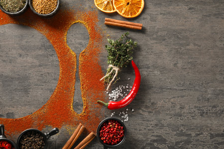 Flat lay composition with different spices, silhouettes of spoon and plate on gray table. Space for textの写真素材