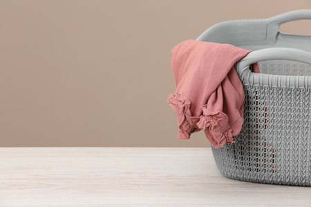 Plastic laundry basket with clothes near beige wall. Space for textの写真素材