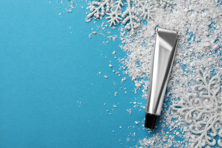 Tube of hand cream and decorative snow on light blue background, flat lay with space for text. winter skincareの写真素材