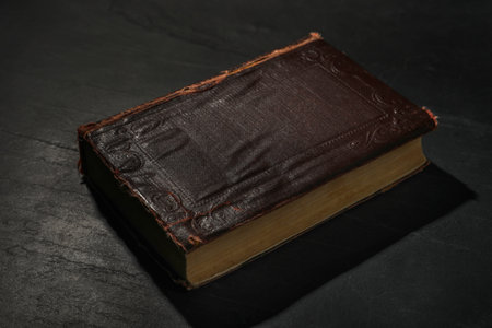 One old hardcover book on black textured tableの写真素材