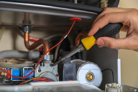 Man repairing gas boiler with screwdriver, closeupの写真素材
