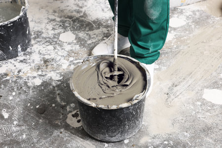 Worker mixing concrete in bucket indoors, closeupの写真素材