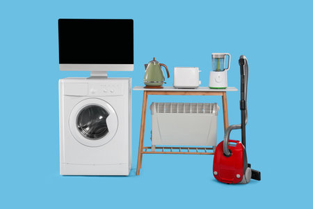 Set of different home appliances with vacuum cleaner on light blue background