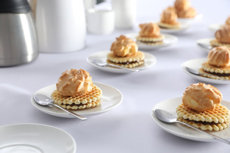 Many delicious waffles with cream served on white table for coffee break