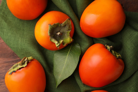 Delicious ripe persimmons on wooden table, flat layの写真素材