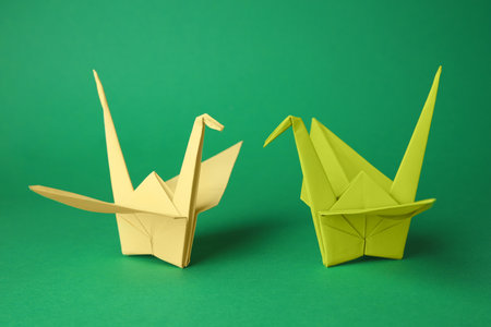 Colorful paper origami cranes on green backgroundの写真素材