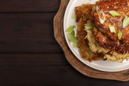 Tasty parsnip cutlets with green onion on wooden table, top view. Space for textの写真素材