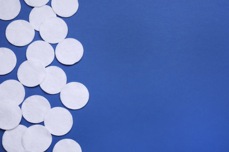 Many cotton pads on blue background, flat lay. Space for textの写真素材