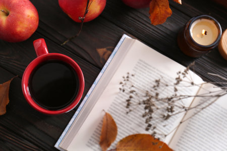 Cup of hot drink, book and ripe apples on wooden table, flat lay. Cozy autumn atmosphereの写真素材