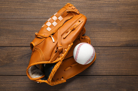 Leather baseball glove with ball on wooden table, top viewの写真素材