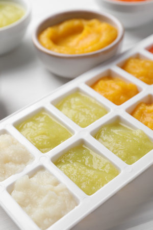 Different purees in ice cube tray on white table, closeup. Ready for freezingの写真素材