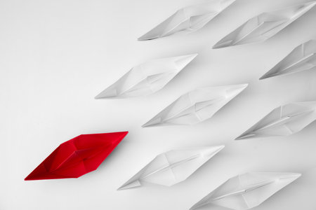 Group of paper boats following red one on white background, flat lay. leadership concept