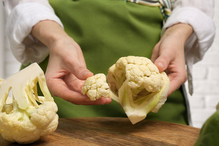 Woman holding fresh cauliflower above wooden board, closeupの写真素材