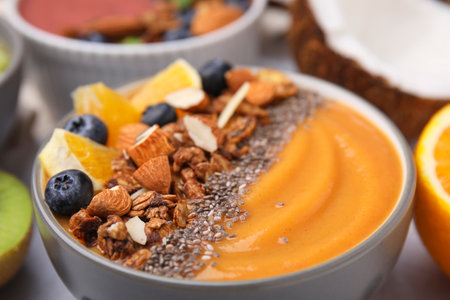 Bowl of delicious fruit smoothie with fresh orange slices, blueberries and granola on table, closeupの写真素材