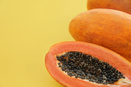 Fresh ripe cut and whole papaya fruits on light green background, flat lay. Space for text