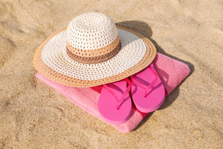 Beach towel with straw hat and slippers on sandの写真素材
