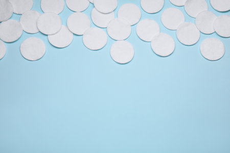 Many cotton pads on light blue background, flat lay. Space for textの写真素材