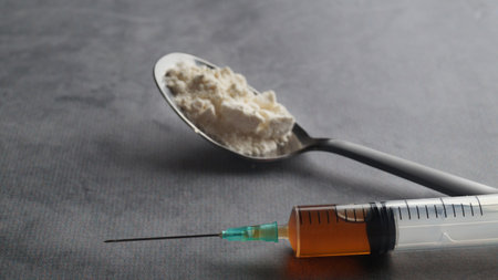 Spoon with powder and syringe on light gray table, closeup. hard drugs