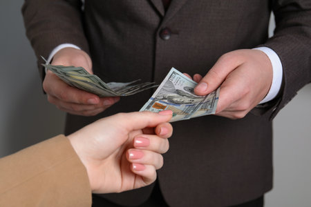 Man giving money to woman on light gray background, closeup. currency exchange