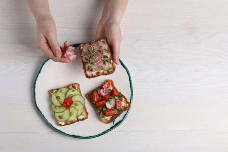 Woman with delicious sandwiches at white wooden table, top viewの写真素材