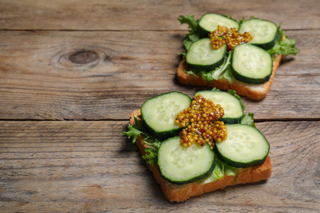 Tasty cucumber sandwiches with arugula and mustard on wooden table, space for textの写真素材