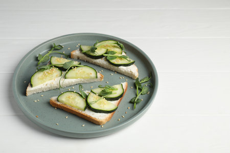 Tasty cucumber sandwiches with sesame seeds and pea microgreens on white wooden tableの写真素材