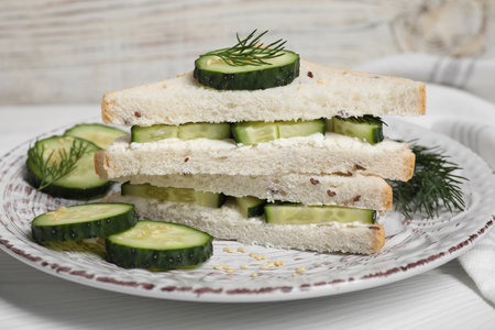 Tasty cucumber sandwiches with sesame seeds and dill on white wooden table, closeupの写真素材