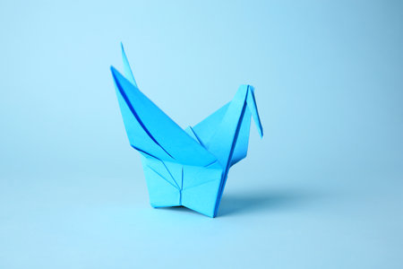 origami art. Handmade paper crane on light blue backgroundの写真素材