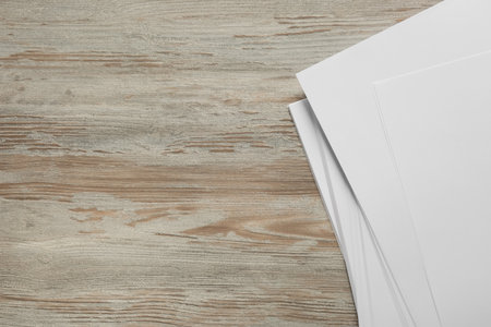 White paper sheets on wooden table, top view. Space for text
