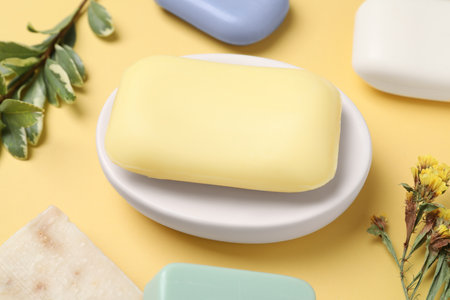 Many soap bars and plant branches on yellow background