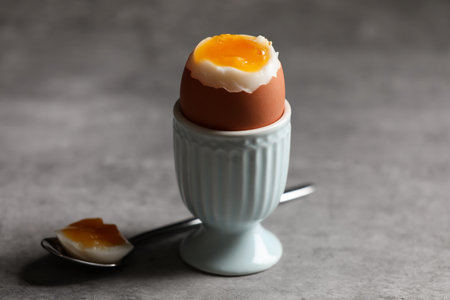 Cup with fresh soft boiled egg on gray table, closeupの写真素材