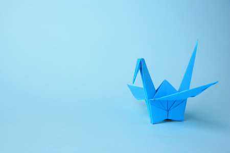 origami art. Handmade paper crane on light blue background, space for textの写真素材